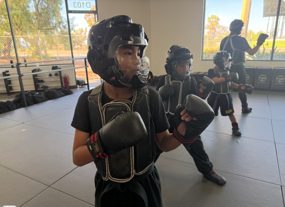 A young student in sparring gear standing ready during a youth class at Legacy Martial Arts